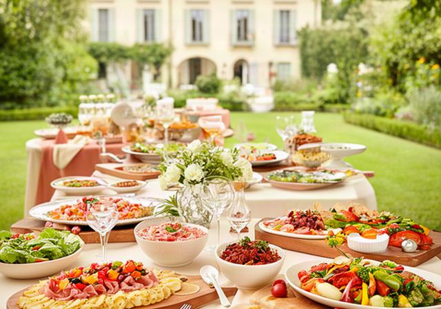 Buffet per comunione in giardino a Verona con isole di antipasti, piatti colorati e decorazioni familiari