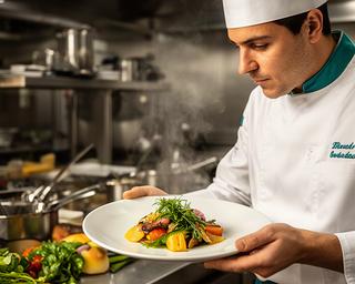 Chef di catering veronese mentre controlla una portata nella cucina professionale