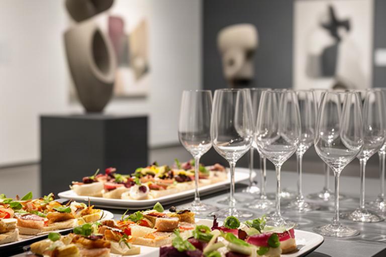 Finger food ordinato e calici disposti in una galleria durante un vernissage